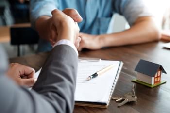 Real estate agent shaking hands with client.